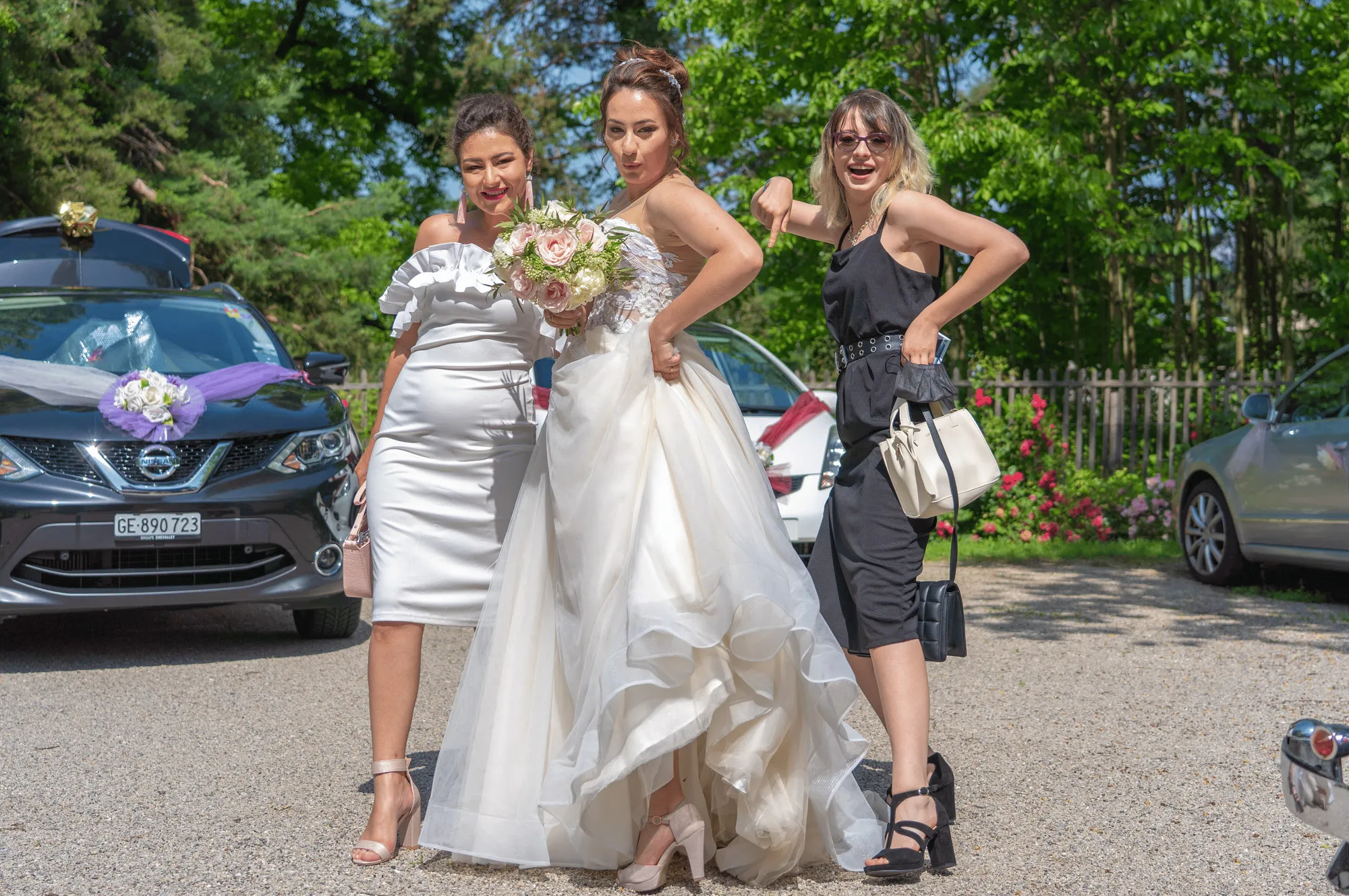 The bride and her friends posing by the car