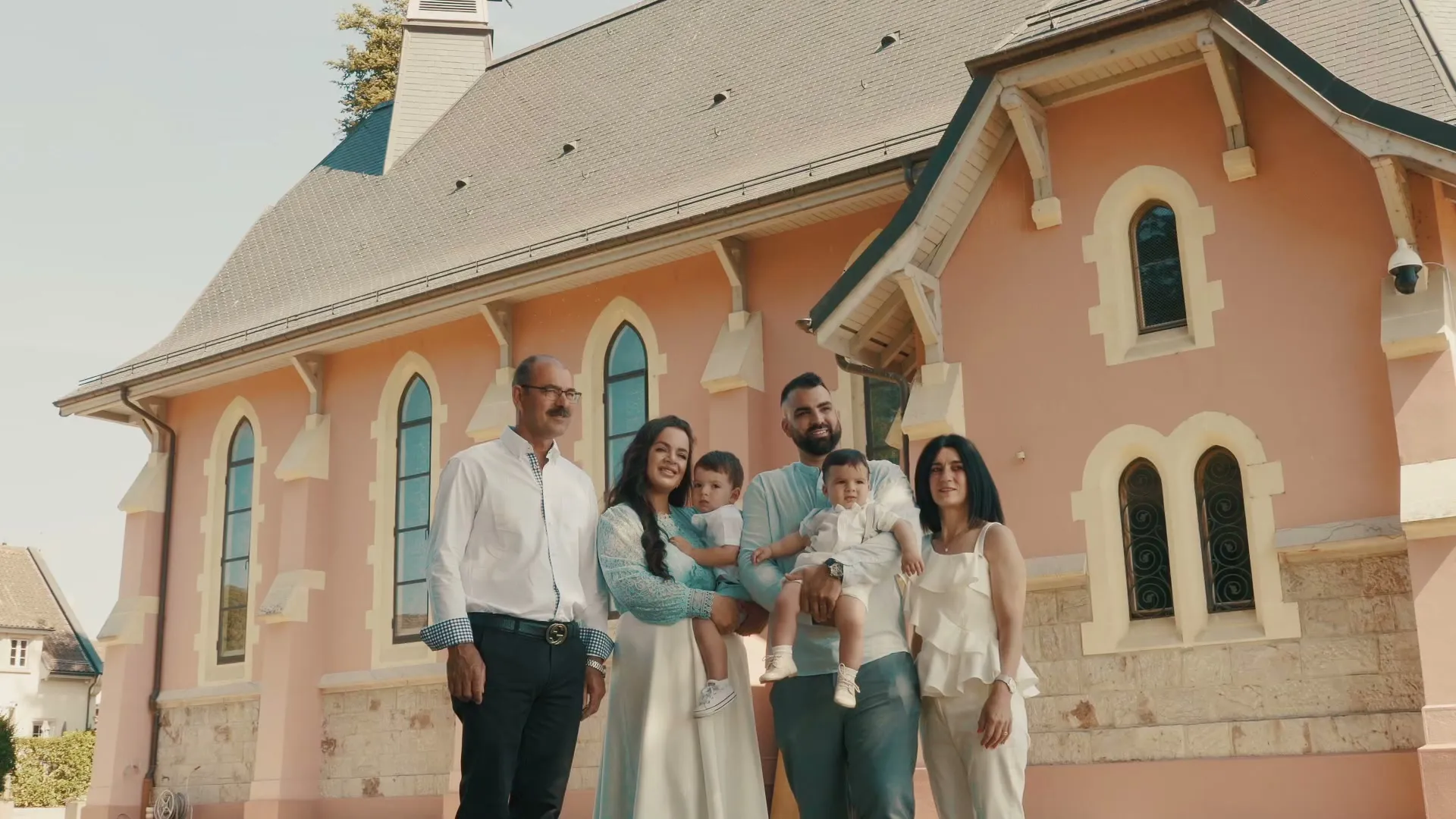 A family gathered in front of a pink chapel