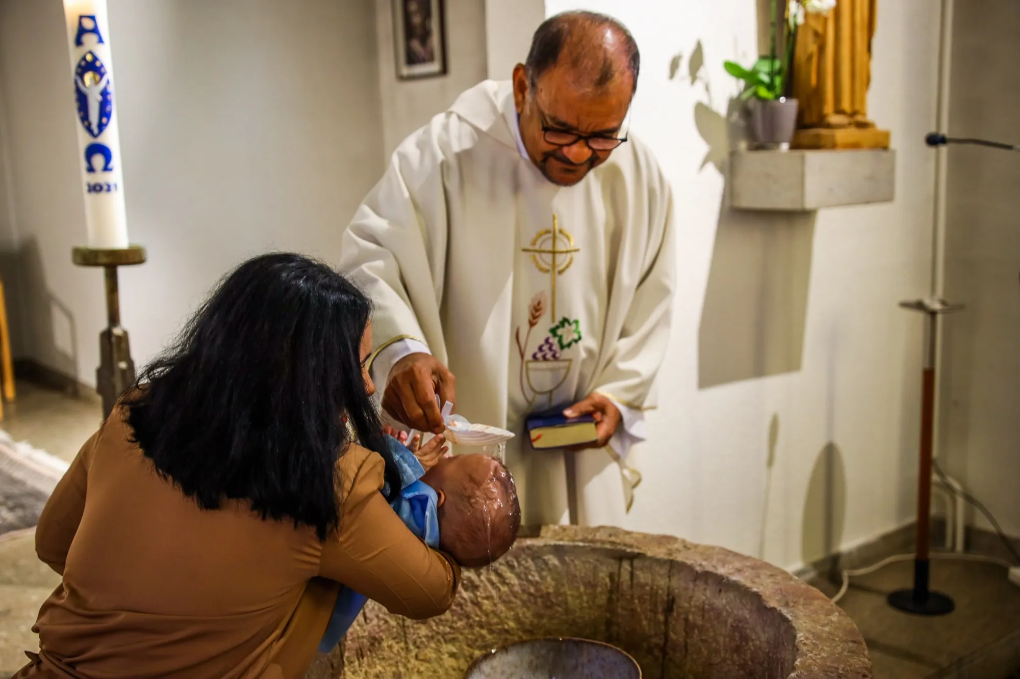 The priest pours the baptismal water over the baby’s head