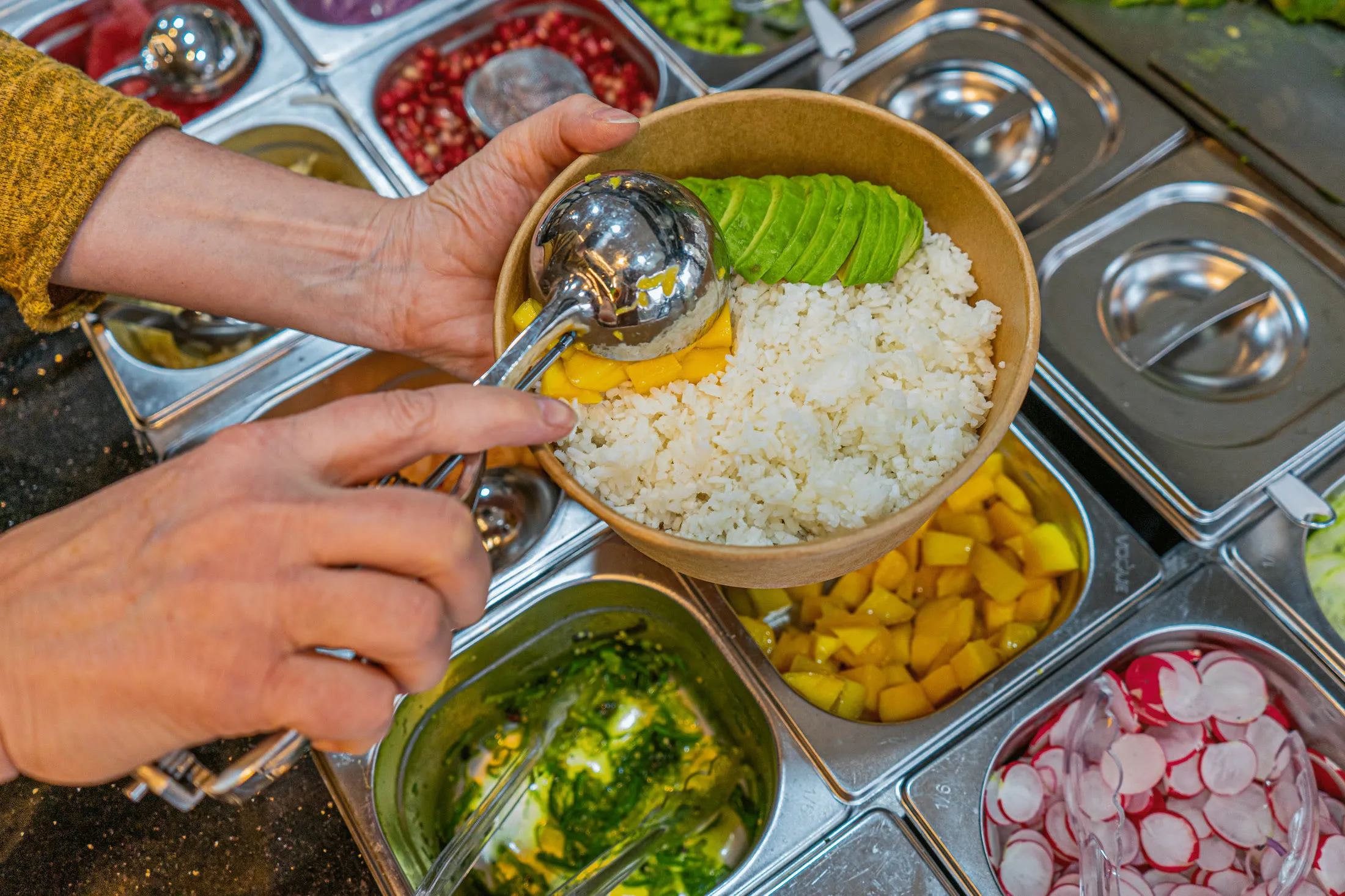 A bowl being assembled from fresh ingredients