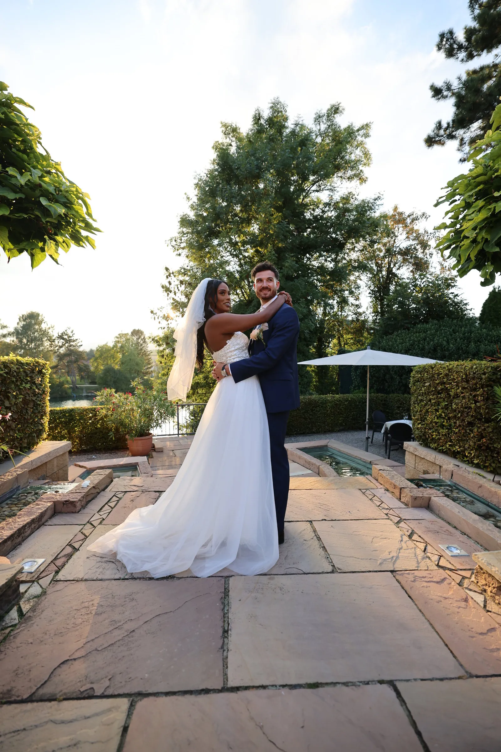 The newlyweds embracing in a garden, white dress and veil