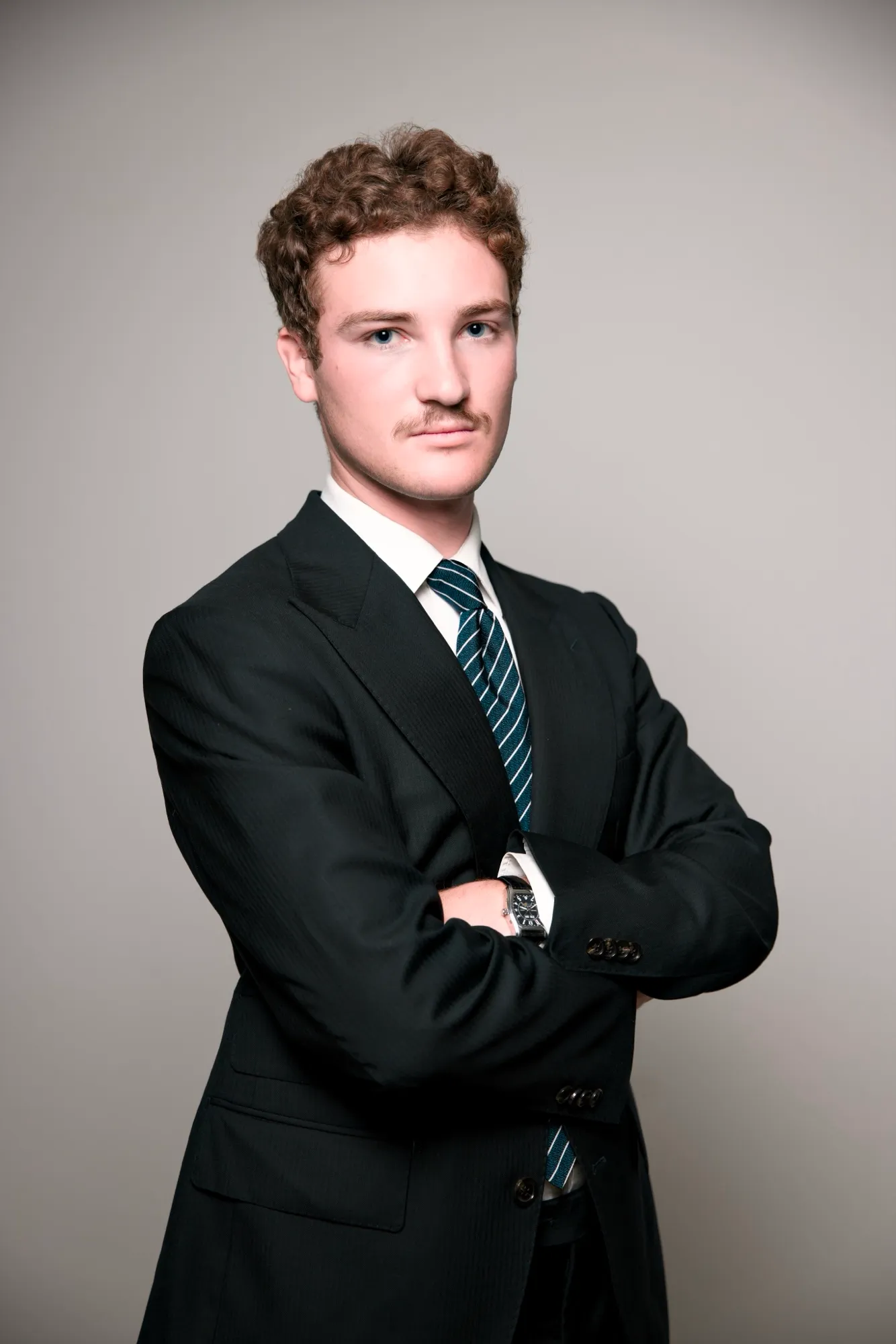 Studio portrait, young man in a suit, arms crossed