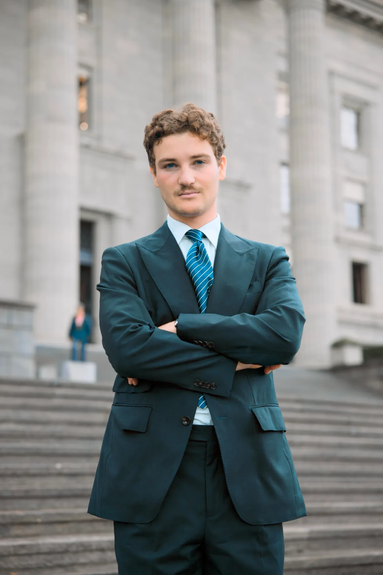 Portrait in front of a colonnaded building, arms crossed